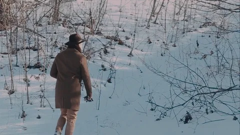 A man in a felt hat and coat comes in the winter woods. brown hat made of felt Stockbeeldmateriaal 72411294