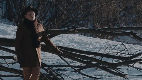 A man in a felt hat and coat comes in the winter woods. brown hat made of felt 動画素材 72411401