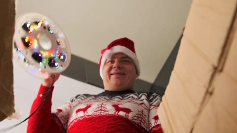 Man in festive xmas clothes dancing is happy about received parcel garlands Stock Footage 255461007