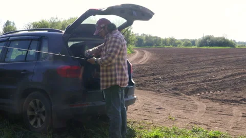 A man in a field opens the boot of a car 스톡 동영상 276723795