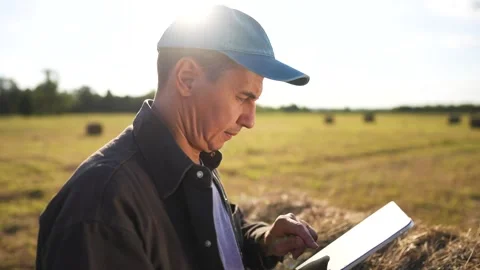 Man in field with tablet. Farmer working on field with haystacks and tablet Video stock 319322607
