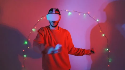Man fighting in vr using swrods with christmas lights in the background Stock Footage 143639447