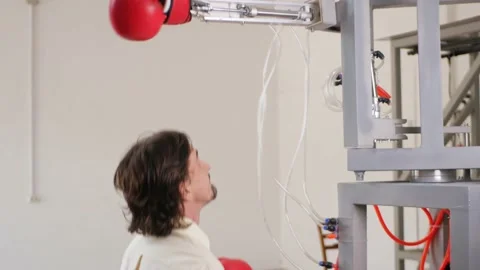 Man fights, trains with mechanical robot boxer. Gloved hand. simulator Stock Footage 204970619