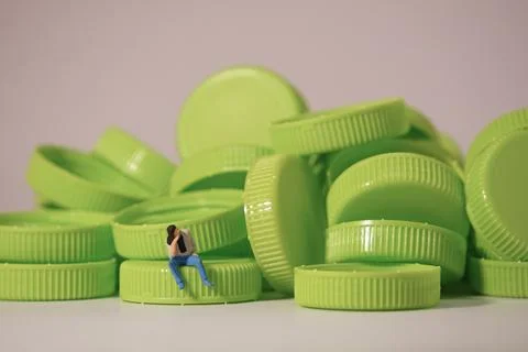 Man figure siting on plastic cap. Recycle material concept. Stock Photos