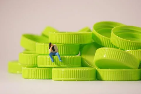 Man figure siting on plastic cap. Recycle material concept. Stock Photos