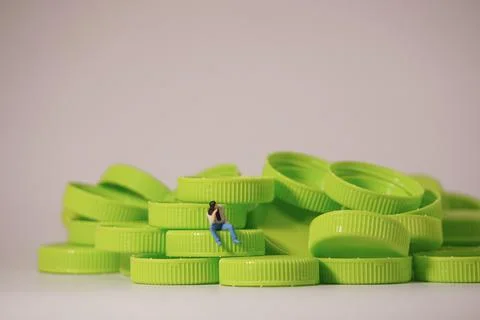Man figure siting on plastic cap. Recycle material concept. Stock Photos