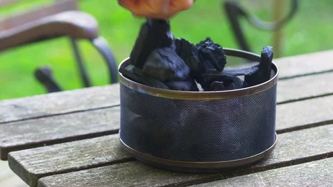 Man filling the coal container of a table grill with charcoal Video stock 77876446