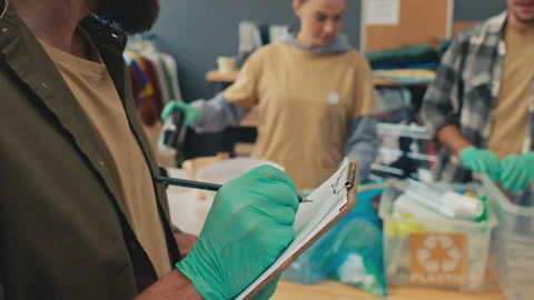 Man Filling Documents while Looking at His Co-workers Sorting Plastic Waste Video stock 251350158