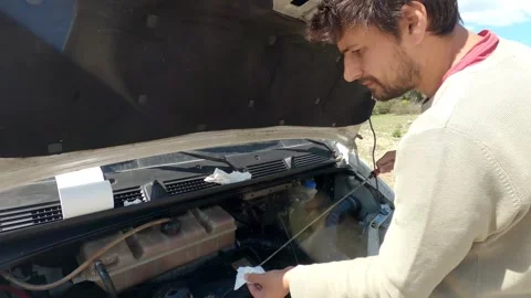 Man filling engine oil during a camper van maintenance in the outdoors Stock Footage 322685603