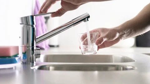 Man filling glass with tap water. Sink in home kitchen. Modern faucet. Stock Footage