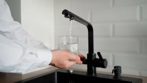 Man fills an empty glass with drinking water in the kitchen Stock Footage 153285830