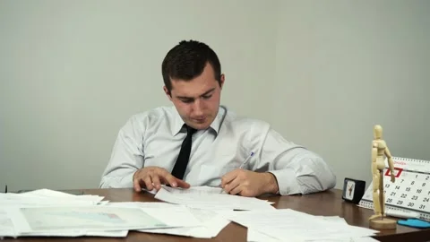 Man fills out documents while sitting at a table in an office Video stock 158830831