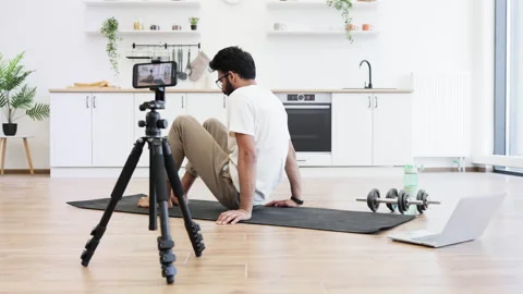 Man filming fitness tutorial performing abs exercises in home kitchen setup 스톡 동영상 316805100