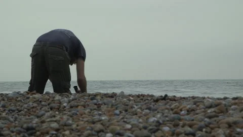 Man Filming On A Pebble Beach Close Up Stock Footage
