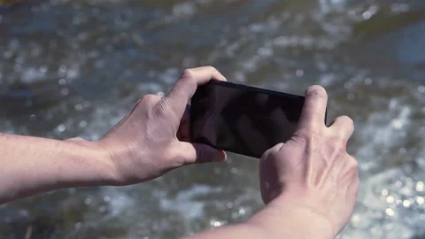 Man filming river on phone. Clip. Close-up of hands with phone on background of Stock Footage