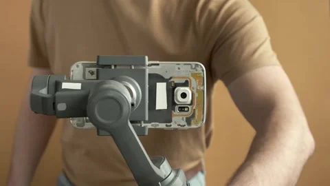 Man filming with a smartphone using a gimbal stabilizer on yellow background Stock Footage 255319038