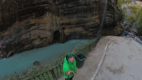 The man films himself against the background of the Chegem waterfalls Stock Footage 195498040