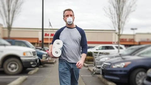 Man in filter mask walking with package of toilet paper Stock Footage 127801330