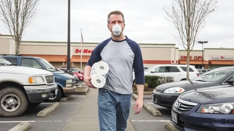 Man in filter mask walking with package of toilet paper Stock Footage 127984650