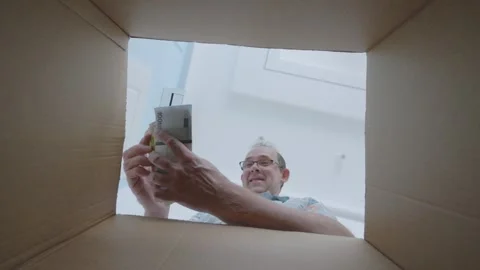 Man finding euros and dollars in a box, expressing surprise and curiosity w.. Stock Footage 295193699
