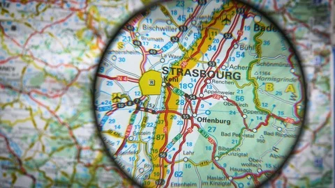 A man is finding Strasbourg on a paper map slowly with a real magnifier Stock Footage 105352956