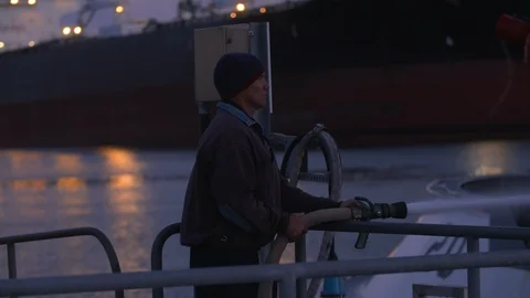 Man with fire hose cleaning fireboat exterior at dusk Port of Long Beach Stock Footage 116471453