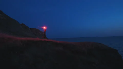 The man with a fire stick running down the mountain near the sea. slow motion Video stock 144040275