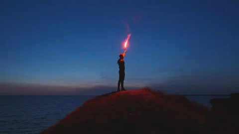 The man with a fire stick standing on the mountain top near the sea. slow motion Video stock 144040658