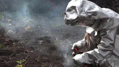 A man in a fireproof suit examines lava flows from the Cabo Verde volcano erupts Video stock 75710156