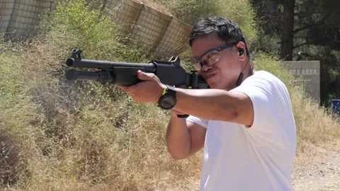 Man fires shotgun and ejects smoking  shotgun shell Stock Footage 276921385