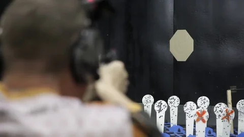 Man firing usp pistol at target in indoor shooting range Stock Footage