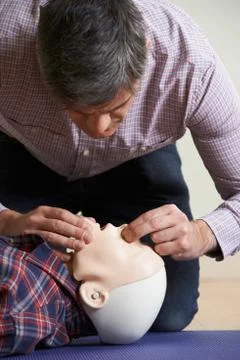 Man In First Aid Class Performing Mouth To Mouth Resuscitation On Dummy Foto stock