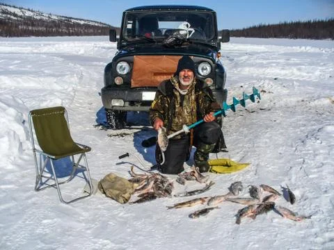 Man with fish catch on ice. Winter fishing on the river. Foto stock
