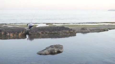 A man fishes on the rocks by the sea. Spain, Alicante Stock Footage 273038053