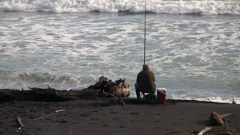 Man fishing on a beach Stock Footage 90210868