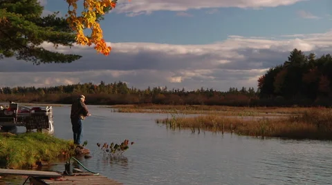 Man fishing off dock during Fall sunset - medium shot Stock Footage 57653342