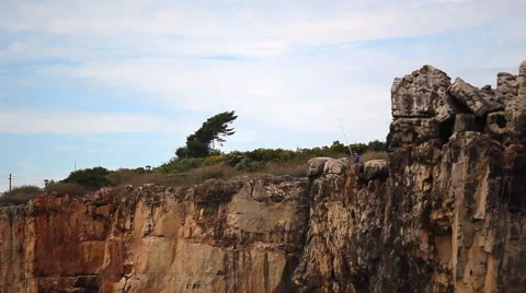 Man fishing with fishing rod from high cliff, Devils Mouth, Portugal Vidéo 59127927