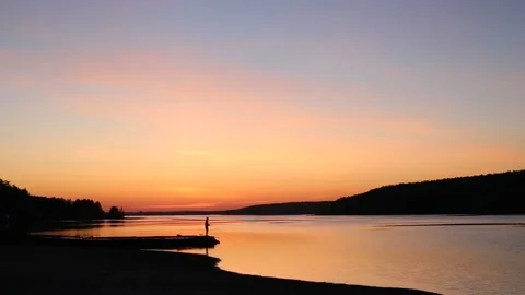 Man is fishing on the river with blue orange pink sunset Stock Footage