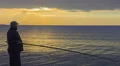 Man fishing at sunrise, enjoying hobby, spending his leisure time with pleasure HD Footage