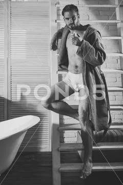 Man with fit body eat apple in underwear, bathrobe, food Stock Photos