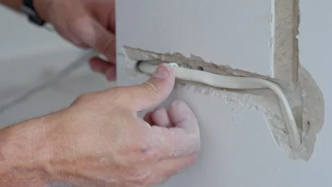 Man fitting electrical cable into channel cut in wall Stock Footage 345006987