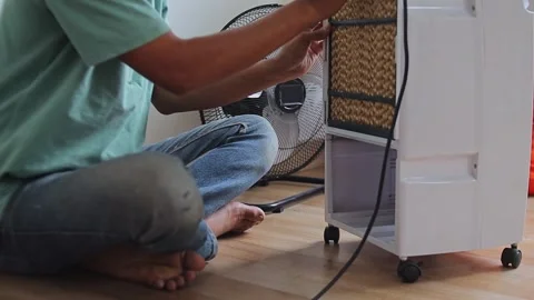 Man fitting evaporative cooling pad into place during home air cooler Stock Footage 347041647