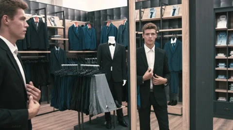 The man in the fitting room, looking in the mirror corrects tie in shop Stock Footage 66428154
