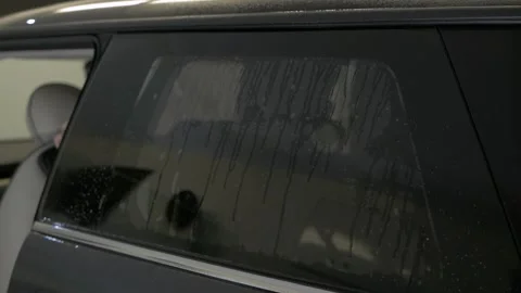 Man fitting tinting foil on side windows from the inside. Filmed from Stock Footage 145730074