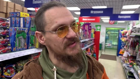 A man in a fixed-price store is talking about goods while looking at the camera. Video stock 234792236