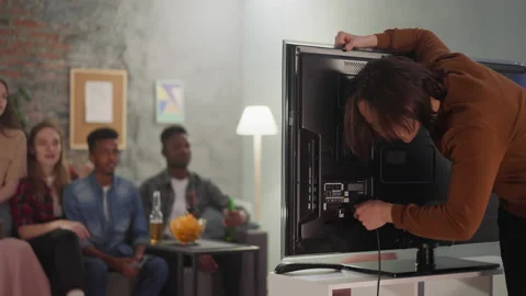 Man fixes broken TV to watch football game with friends Stock Footage