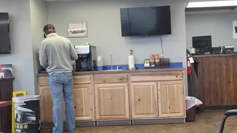A man fixes coffee in a clean auto repair breakroom, waiting room 库存影片 340236942