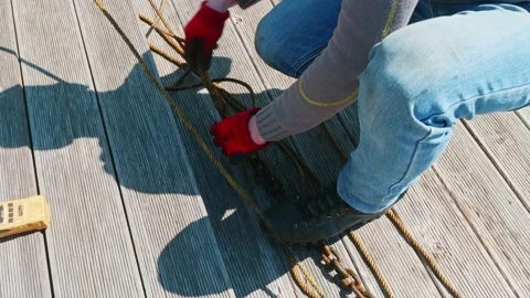Man fixes cords of tug on small bollard on wooden pier. Up view. Stock Footage 153996756
