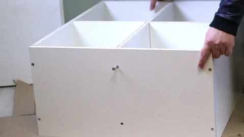 A man fixes partitions in a shelving unit. With Euroscrews. Wooden modular .. Video stock 228313428