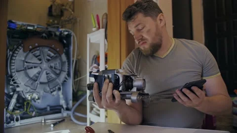 A man fixes a washing machine and watches instructions on his phone Stock Footage 155644836